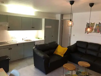 a living room with a black couch and a kitchen at Acacia 1 Hengelhoef in Houthalen-Helchteren