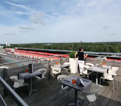a man standing on a rooftop with tables and chairs at Hotel De Pits in Heusden - Zolder
