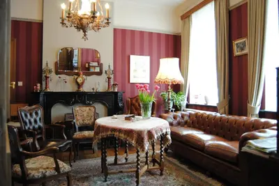 a living room with a leather couch and a table at B&B Het Loonderhof in Borgloon