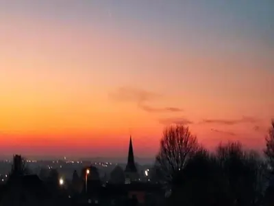 a sunset over a city with a church steeple at Cozy Villa in Dalhem Ardennes with Private Garden in Dalhem