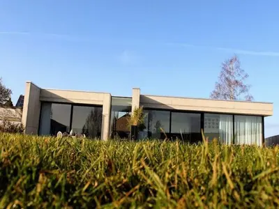 a building with glass windows on a field of grass at Cozy Villa in Dalhem Ardennes with Private Garden in Dalhem