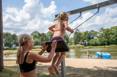 a woman is helping a little girl on a swing at Familiepark Goolderheide in Bocholt