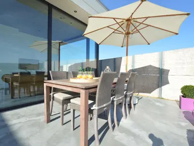 a wooden table with chairs and an umbrella on a patio at Modern Dalhem Villa with Views in Dalhem