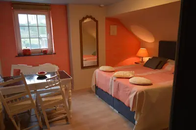 a bedroom with a bed and a table and a mirror at Julienne5 in Blégny