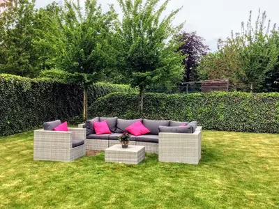 a couch with pink pillows sitting in a yard at B&B Villa Curtricias in Kortessem