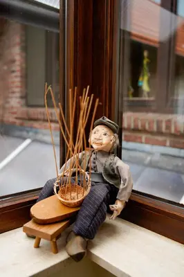 a toy boy sitting on a window sill with a basket at De Mandenvlechter in Dilsen-Stokkem