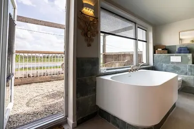 a bath tub in a bathroom with a large window at Maas Suites (Maastricht - Lanaken) in Lanaken