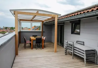 a deck with a table and chairs on a roof at LA BINAMERIE in Remicourt