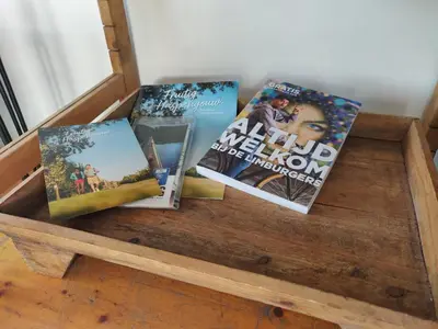 four books sitting on top of a wooden table at Wetterdelle Lodge in Heers