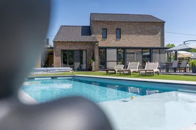 a swimming pool in front of a house at Bed & Breakfast 't Vèèrke in Dilsen-Stokkem