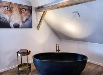 a bathroom with a large black tub in a attic at De Bonderbei in Wellen