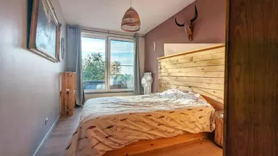 a bedroom with a bed with a wooden headboard and a window at Maison à la porte des Ardennes in Verviers