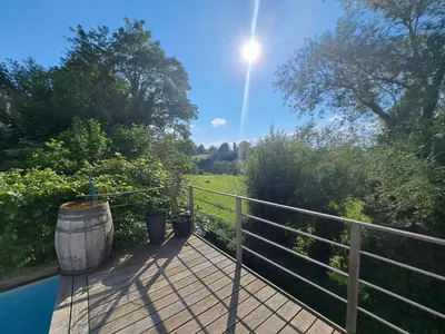 a wooden deck with a barrel and a fence at Maison à la porte des Ardennes in Verviers