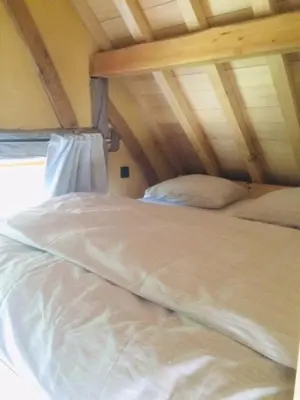 a white bed in a room with a wooden ceiling at Boerderaaj vakantiewoning in Bilzen