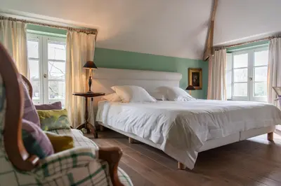 a bedroom with a white bed and a chair at Hotel De Barrier in Houthalen-Helchteren