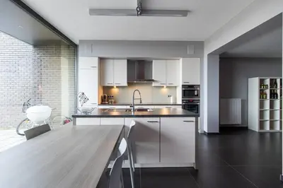 a kitchen with white cabinets and a wooden table at La Maison de Marie in Borgloon