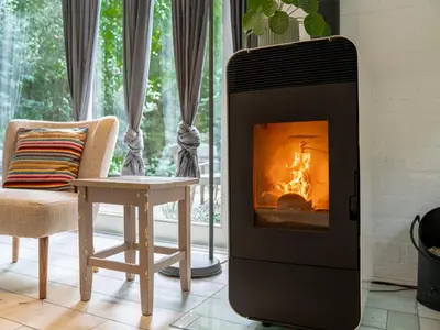 a fireplace in a living room with a chair and a table at Boshuisje Rekem - Luka in Lanaken