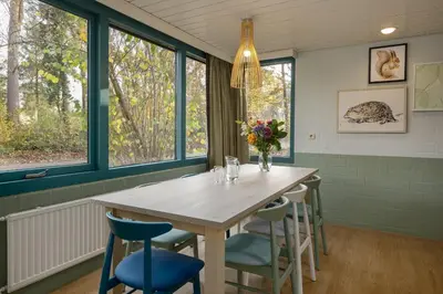a dining room with a table and chairs and windows at Center Parcs Erperheide in Peer