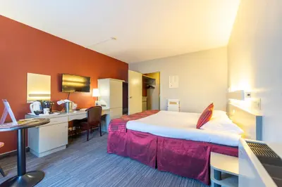 a hotel room with a large bed and a desk at Hotel Ambiotel in Tongeren