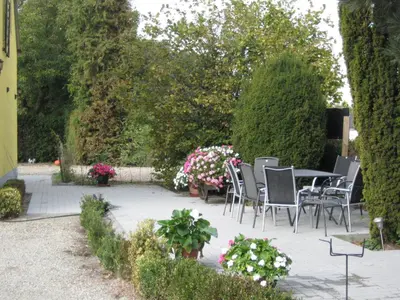 a patio with a table and chairs and flowers at B&B Het Uilennest in Bocholt