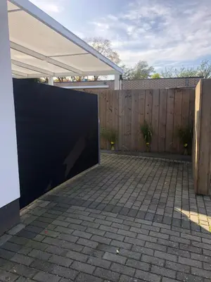 a backyard with a black wall and a fence at Vivere in Houthalen-Helchteren