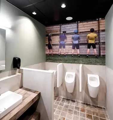 a bathroom with three urinals and a mural of three baseball players at Café Coureur Borgloon in Borgloon