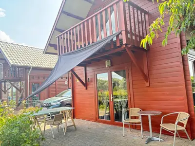 a red house with a patio with chairs and a table at Thuiskomen, genieten aan het water in Maaseik