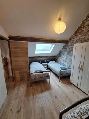 a bedroom with two beds and a stone wall at Gîte Cour Delhez in Olne