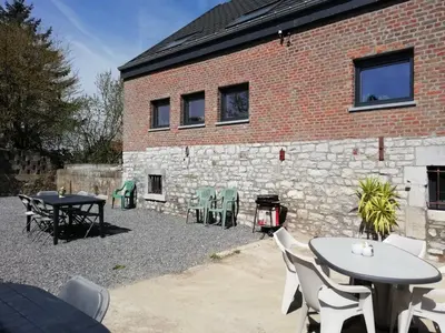 a patio with tables and chairs in front of a brick building at Gîte Cour Delhez in Olne