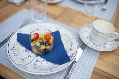 a plate with a cup and a bowl of fruit on a table at B&B Gaudium XII in Tongeren