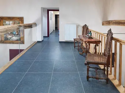 a hallway with a blue tile floor with a table and chairs at B&B Hoeve De Brieser in Heers