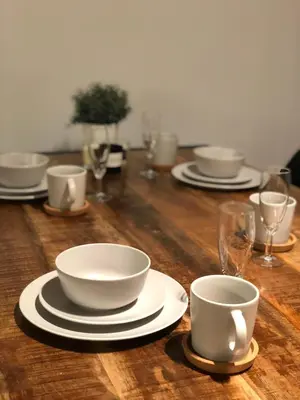a wooden table with white cups and plates and wine glasses at De Konik in Uikhoven