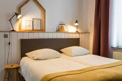 a bedroom with two beds and a mirror on the wall at VillaEnzo - ELEGANT HERENHUIS - 14P - 6SLPK - SAUNA - INFRAR CABINE - OFYR BBQ - 15MIN Maastricht in Zussen