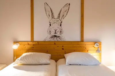 a painting of a rabbit on the wall above a bed at ZussEnzo - STOER FAMILIEHUIS - 18P - 5SLPK - GROTE TUIN - SAUNA - OFYR BBQ - HOMECINEMA - 15MIN MAASTRICHT in Zussen