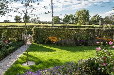 a garden with flowers and a fence at PuurTeuven B&B tussen Kunst en Natuur in Voeren