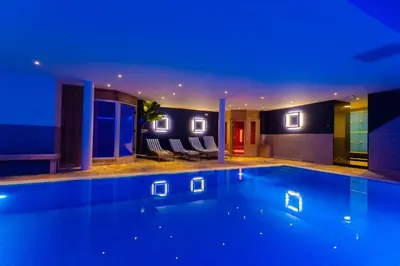a swimming pool with blue lights in a house at Hotel Pracha in Borgloon