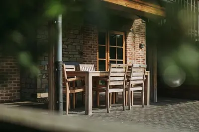 a wooden table and chairs outside of a brick building at Kamphuis Heideven in Peer
