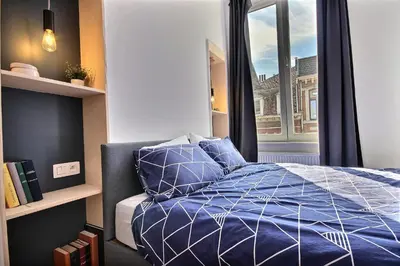 a bedroom with a blue bed with a window at Tokyo's Place in Liège