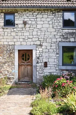 a stone building with a wooden door and flowers at Vakantiewoning Veurservallei in Voeren