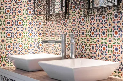 a bathroom with a white sink and a tile wall at Ryad Mogador Liège in Liège