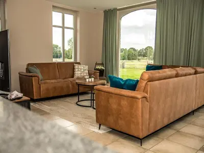 a living room with leather furniture and a large window at Peaceful Peer Holiday Home in Peer