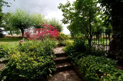 a garden with a fence and some bushes and flowers at De Zwarte Stok in Riemst