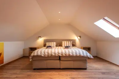 a attic bedroom with a bed and a skylight at NEW - De sheeper - 10Personen - 5slaapkamers - Sauna - Jacuzzi in Riemst