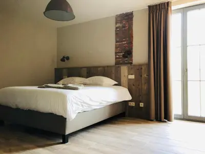 a bedroom with a bed and a large window at B & B De Romeinse Katzei in Borgloon