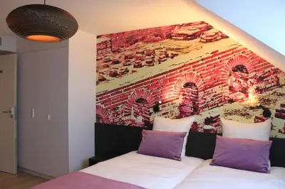 a bedroom with a brick wall and a bed with purple pillows at B&B Atuatuca in Tongeren