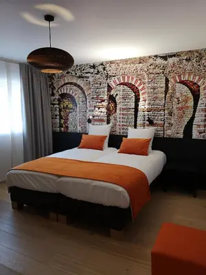 a bedroom with a large bed with a brick wall at B&B Atuatuca in Tongeren