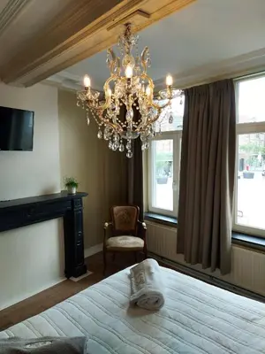 a bedroom with a large bed and a chandelier at Logies Mario in Tongeren