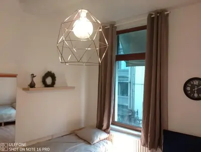 a room with a bed and a window with a clock at Logement Régence in Liège