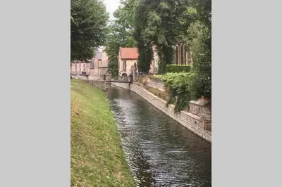 a view of a river with a building in the background at Villa Domus XIX in Tongeren