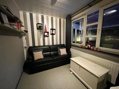 a living room with a black couch and a window at Villa Domus XIX in Tongeren